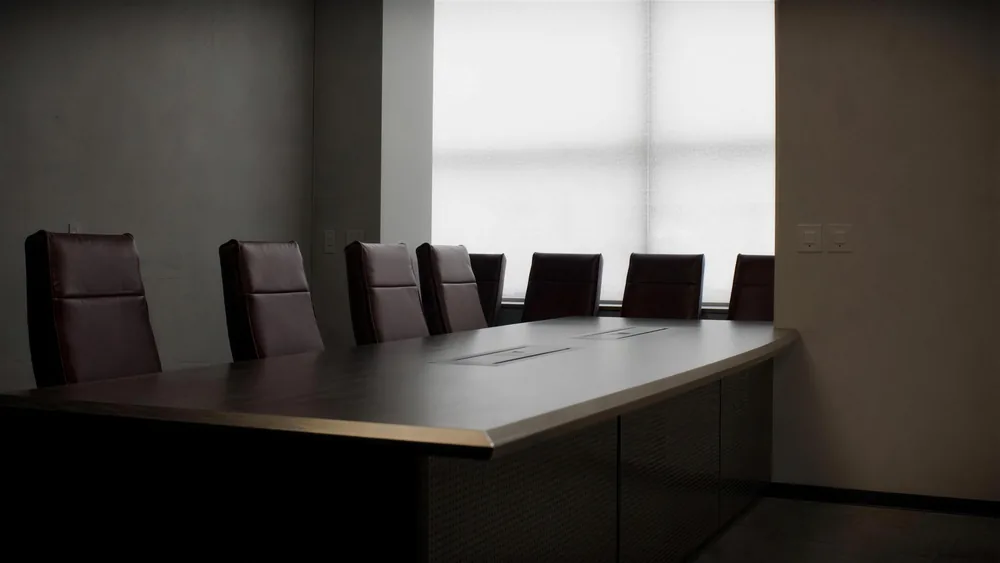 Pusta sala konferencyjna z długim ciemnym stołem i skórzanymi krzesłami